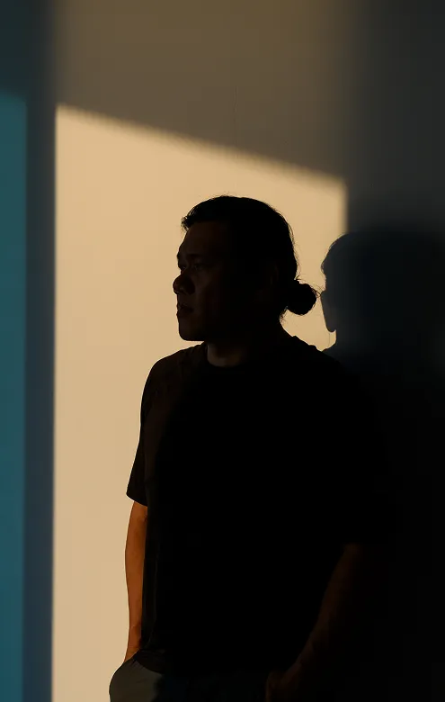 Silhouette of a person standing alone by a window