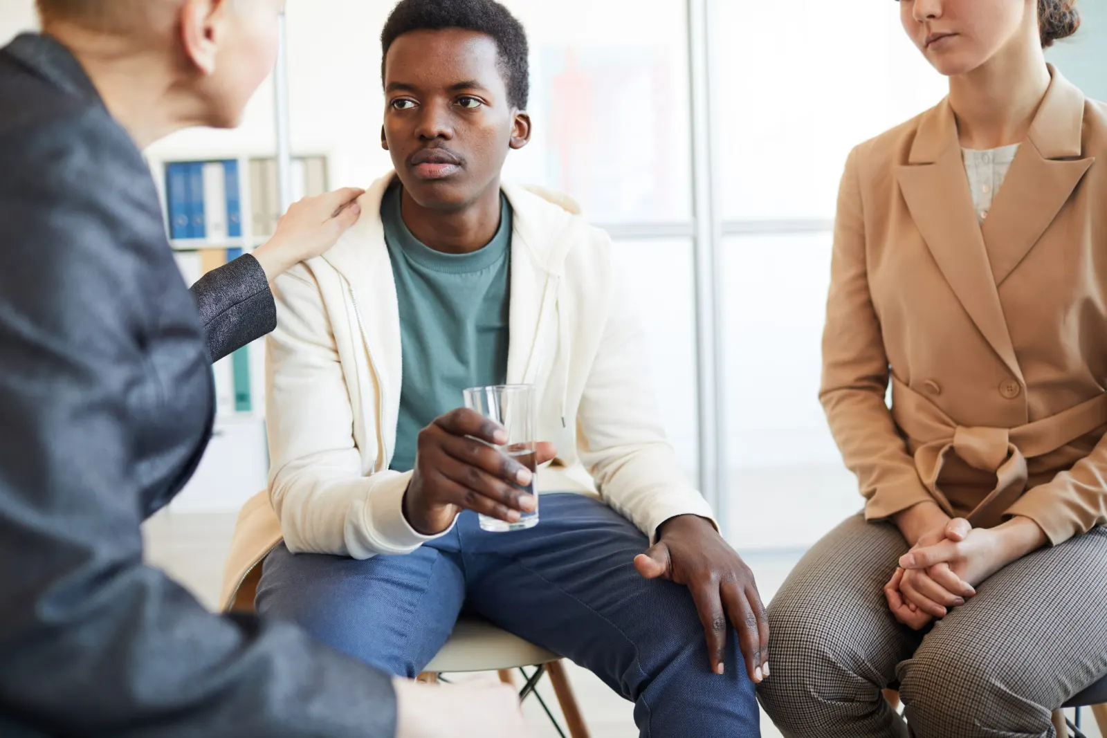Young man talking with two counsellors in a support session